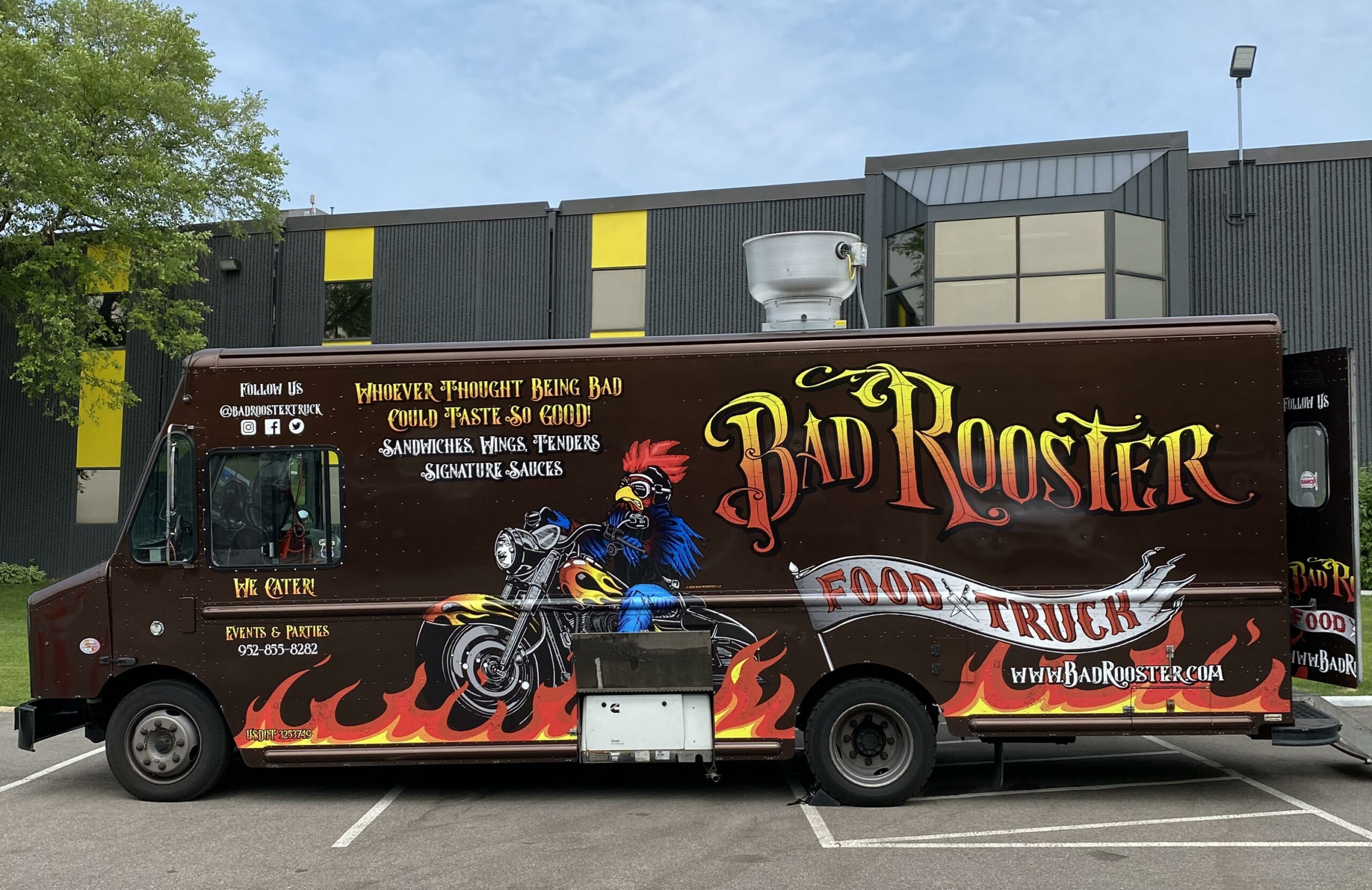 food truck with image rooster on motorcycle parked outside a gray building